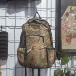 Camouflage backpack hanging on display wall.