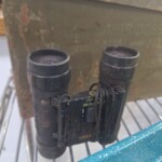 Old binoculars on a metal shelf.