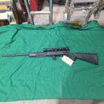 Black rifle with scope on green cloth