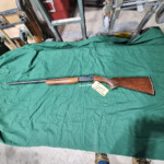 Shotgun with wooden stock on green cloth