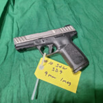 9mm handgun with yellow tag on green cloth