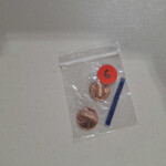 Clear bag with two pennies and orange sticker