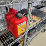 Red one-gallon gasoline can on metal shelf
