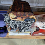 Colorful folded fringed blanket on shelf