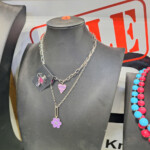 Mannequin displaying layered silver necklaces with purple pendants