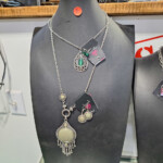 Black mannequin displaying layered silver necklaces with pendants