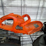 Orange electric hedge trimmer on shelf