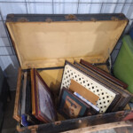 Open vintage trunk filled with framed pictures