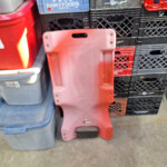 red plastic mechanic creeper leaning against crates
